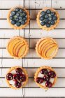 Disposizione di tartellette ripiene di panna e ciliegie viste dall'alto — Foto stock
