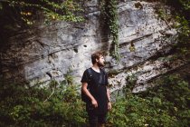 Mann posiert über mit Pflanzen bewachsene Klippe in der Natur — Stockfoto