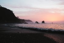 Malerischer Blick auf die wunderschöne Küste und den Ozean im rosafarbenen Sonnenuntergang. — Stockfoto