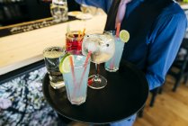 Kellner hält Tablett mit verschiedenen Cocktails an der Theke. — Stockfoto