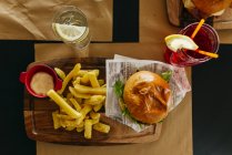 Dall'alto hamburger appetitoso con patatine fritte servite sul tavolo in caffè . — Foto stock