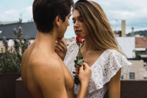Portrait of sensual man embracing girl and touching her face with rose — Stock Photo