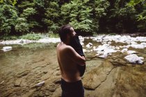 Hombre de vista lateral limpiando con toalla en el río en el bosque . - foto de stock