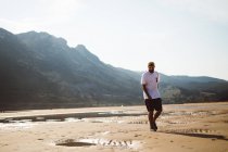 Vista frontal do homem andando na praia sobre a costa de prumo no fundo — Fotografia de Stock