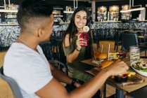 Mulher sorridente com bebida olhando para o homem no café — Fotografia de Stock