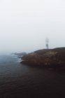 Landscape of foggy lighthouse on rocky coastline — Stock Photo