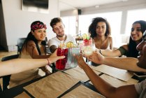 Glückliche Freunde stoßen am Café-Tisch auf Cocktails an — Stockfoto