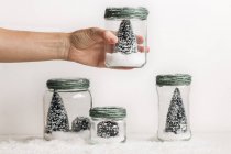 Hand holding decorative Christmas tree in jar over white background — Stock Photo