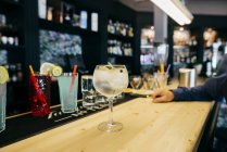 Cocktail on bar counter and hand of unrecognizable man. — Stock Photo