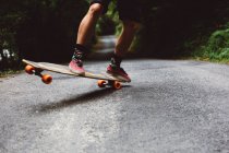 Crop man sur skateboard sur tricking sur route asphaltée — Photo de stock