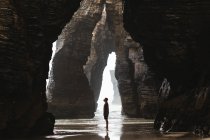 Vista lateral do homem em pé na caverna costeira — Fotografia de Stock