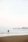 Surfer Mann läuft in Wellen am Strand — Stockfoto
