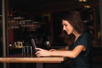 Вид сбоку жизнерадостной женщины за ноутбуком за столиком кафе — стоковое фото