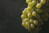 Vista de cerca del racimo de uvas verdes sobre fondo oscuro - foto de stock