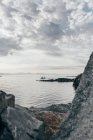 Морской пейзаж с плавучей лодкой на спокойной воде в пасмурный день . — стоковое фото