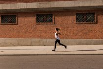 Side view of sportive girl jogging on sidewalk — Stock Photo