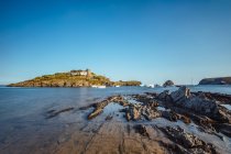 Paesaggio costiero di collina illuminata dal sole con case rurali a baia di mare — Foto stock