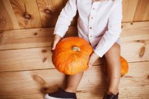 Crop kid sitting on floor and holding pumpkin — Stock Photo
