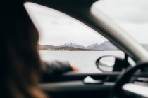 Невпізнанним людина за кермом автомобіля біля гори озера похмурий день. — стокове фото