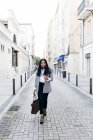 Elegante donna d'affari sorridente con borsa che cammina per strada e guarda la fotocamera
. — Foto stock