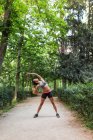 Sporty girl performing yoga asana at park alley on sunny summer day — Stock Photo