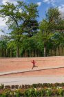 Vista lateral da menina correndo no parque da cidade — Fotografia de Stock