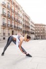 Vue latérale de la femme sportive échauffant le corps sur la scène de rue — Photo de stock