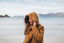 Femme brune souriante portant une capuche posant sur un lac de montagne
. — Photo de stock