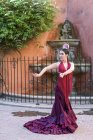 Bailarina flamenca vestida con el típico traje hispano posando sobre una fuente callejera de fondo - foto de stock