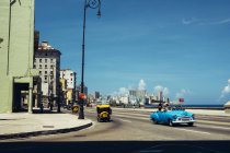 CUBA - 27 de agosto de 2016: Vista do carro retro na estrada da antiga cidade costeira sob o céu azul — Fotografia de Stock