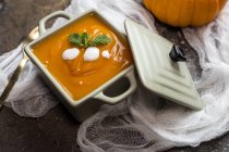 Still life with cream of pumpkin in ceramic square bowl — Stock Photo