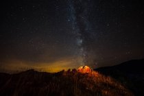Tenda turistica illuminata sulla collina sullo sfondo della via lattea nel cielo notturno — Foto stock