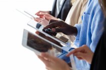 Crop of row of multhiethnic business people browsing tablets — Stock Photo