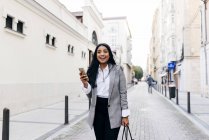 Портрет веселой женщины, идущей с телефоном по улице — стоковое фото