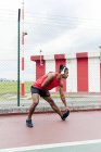 Esportista ouvir música e esticar as pernas antes do treino — Fotografia de Stock
