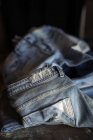 Закрыть вид на синие джинсовые штаны на темном столе . — стоковое фото