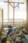 Benin, afrika - 30. august 2017: schwarzer mann liegt mit flasche im bett im krankenhaus und blickt in kamera — Stockfoto