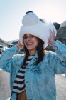 Laughing girl in denim coat standing on road and wearing panda toy head — Stock Photo