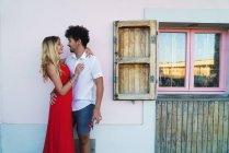 Loving passionate couple embracing beside window with opened shutters — Stock Photo