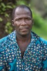 Benin, afrika - 31. august 2017: porträt eines mannes im bunten blauen hemd, der in die kamera blickt. — Stockfoto