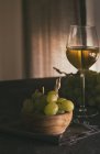 Stillleben von grünen Trauben mit Spießen in Schüssel und Glas Weißwein auf dem Tisch — Stockfoto