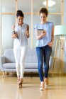 Front view of two business woman walking in modern office. — Stock Photo