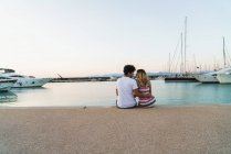 Rear view of couple embracing on pier with moored yachts — Stock Photo