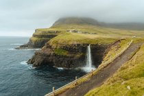 Панорамный вид на побережье с водопадом, падающим в океан — стоковое фото