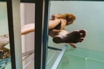 Нижний вид топлесс женщины, идущей по стеклянному полу — стоковое фото
