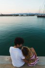 Rückansicht eines glücklichen Paares, das auf der Seebrücke sitzt und Spaß hat — Stockfoto
