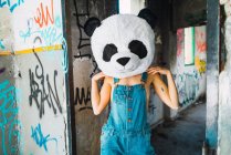 Porträt eines Mädchens im Overall mit Plüsch-Panda-Kopf posiert vor verlassenem Gebäude — Stockfoto