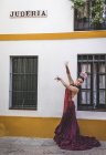 Танцовщица фламенко позирует рядом со зданием с надписью на фасаде — стоковое фото