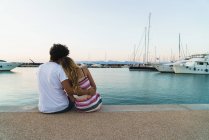 Back view of couple embracing on pier with moored yachts — Stock Photo