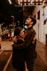 Пара обнимается и смеется на вечерней улице — стоковое фото